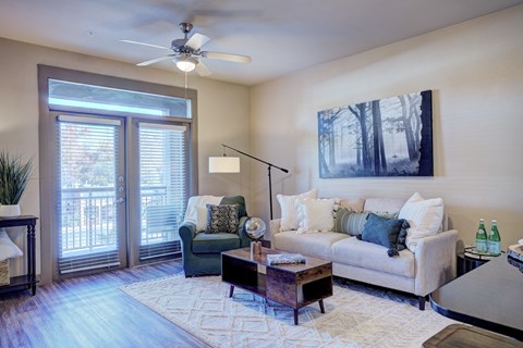 a living room with a couch and a chair and a ceiling fan